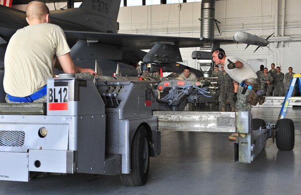 SHAW AIR FORCE BASE, S.C. -- Staff Sgt. Christopher Benton Jr. (right) and Airman 1st Class Nicole Nuemann (center), 55th Aircraft Maintenance Unit, directs a missile into place while Airman 1st Class Ryan Whitehead drives the bomb lift truck April 16, 2010. Wing weapons standardization held the first Weapons Load Crew of the Quarter competition for 2010. The 55th and 79th Aircraft Maintenance Units weapons load crews competed against each other in a race against time. Both load crews were tasked to load two air intercept missiles, or AIM - 120s, and two air-to-ground missiles, also known as AGM - 88s, within 45 minutes. (U.S. Air Force photo/Airman 1st Class Amber E. N. Jacobs)