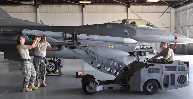 SHAW AIR FORCE BASE, S.C. -- Airman 1st Class Nicole Nuemann (left) and Staff Sgt. Christopher Benton Jr. (center), 55th Aircraft Maintenance Unit, direct a missile into place, while Airman 1st Class Ryan Whitehead drives the bomb lift truck April 16, 2010. Wing weapons standardization held the first Weapons Load Crew of the Quarter competition for 2010. The 55th and 79th Aircraft Maintenance Units weapons load crews competed against each other in a race against time. Both load crews were tasked to load two air intercept missiles, or AIM - 120s, and two air-to-ground missiles, also known as AGM - 88s, within 45 minutes. (U.S. Air Force photo/Airman 1st Class Amber E. N. Jacobs)