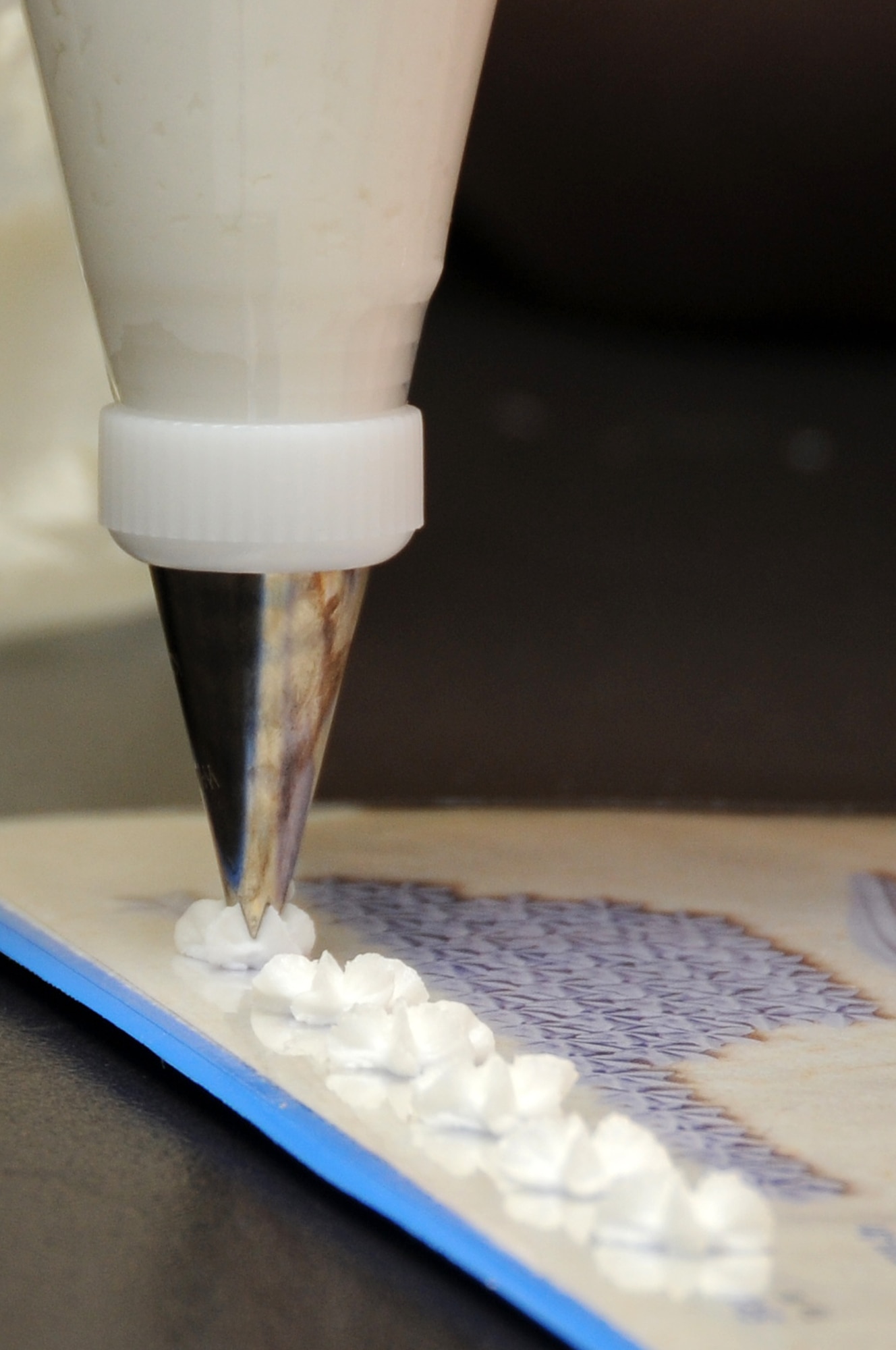 A two-part device consisting of a base and ring called a coupler is used to decorate cakes. The coupler has different tips that can be used to achieve many different results to include making stars (pictured), dots, and swirls.(U.S. Air Force photo by Airman 1st Class Lausanne Morgan)