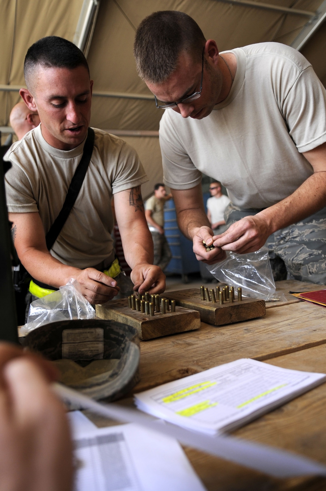Senior Airmen Drew Evan Green (left) and Kurtis Franklin, both C-130J crew chiefs, 451st Expeditionary Aircraft Maintenance Squadron, confirm the accurate amount of ammunition before signing for the issued items. Airman Green is turning in ammunition and Airman Franklin, newly assigned to the unit, is being issued ammunition. The Combat Arms Training and Maintenance team at the 451st Expeditionary Security Forces Squadron ensures all Air Force members are issued ammunition and weapons upon arrival at Kandahar Airfield.   (U.S Air Force photo by Senior Airman Nancy Hooks/Released)