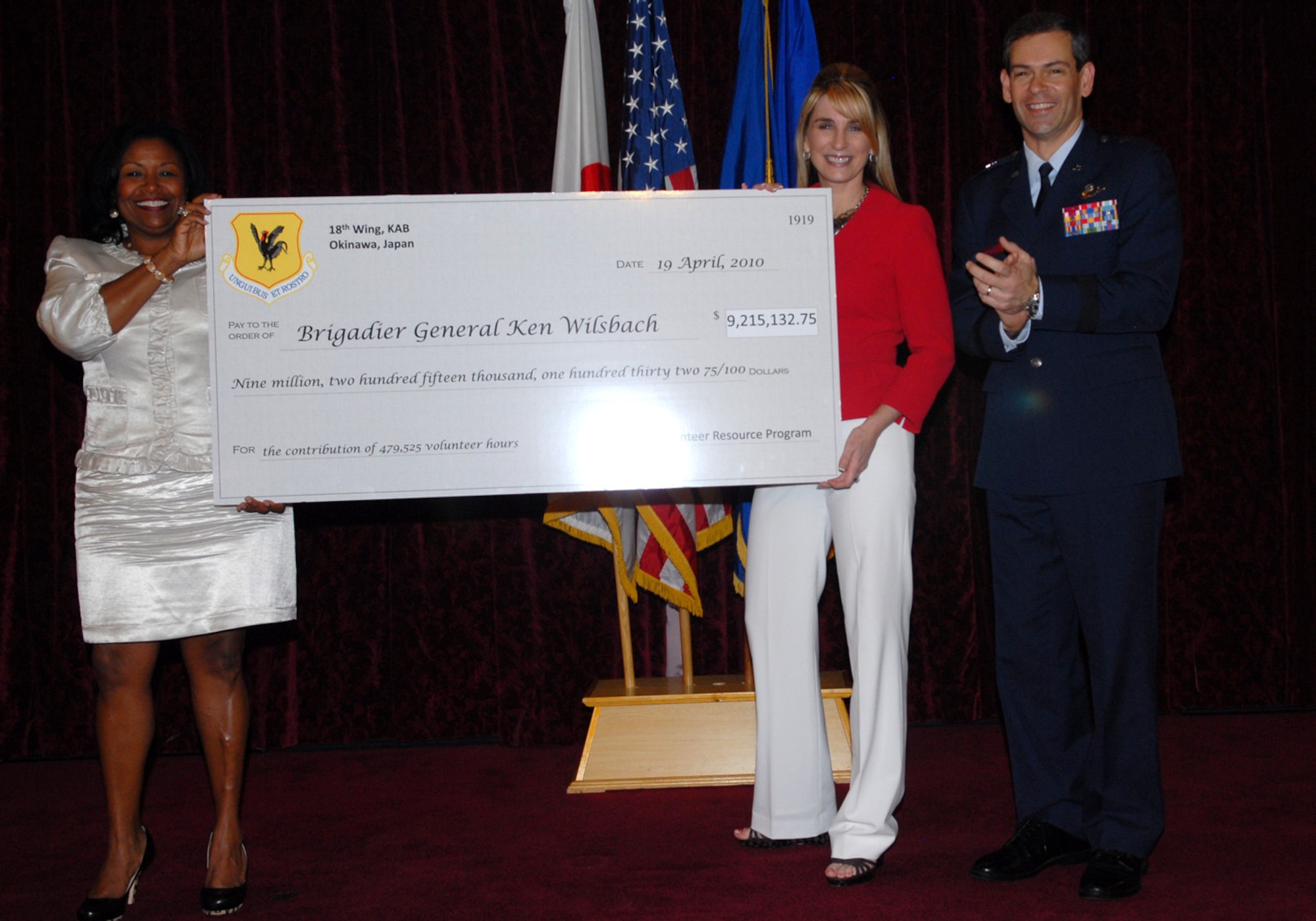 Ms. Jiri Crowder, Kadena Airman and Family Readiness Center chief, presents Brig. Gen. Ken Wilsbach, 18th Wing commander, and his wife Cindy with a symbolic check worth $9,215,132.75 – the dollar value of the 479,525 volunteer hours contributed by Kadena volunteers over the course of 2009. 
(U.S. Air Force photo / Junko Kinjo)

