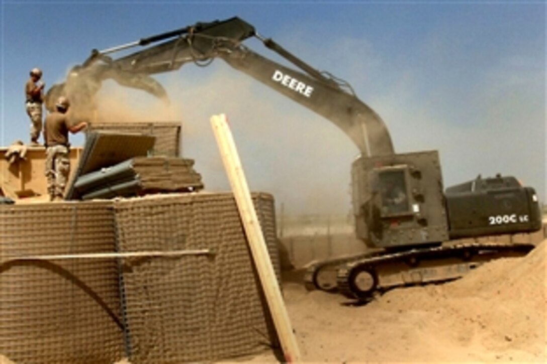 U.S. Navy Seabees use an excavator and shovels to fill barriers with sand during construction of a security wall in Tarnak, Afghanistan, April 9, 2010.  The Seabees are assigned to Naval Mobile Construction Battalion 133, Detachment 6, which is in the U.S. Central Command area of responsibility.