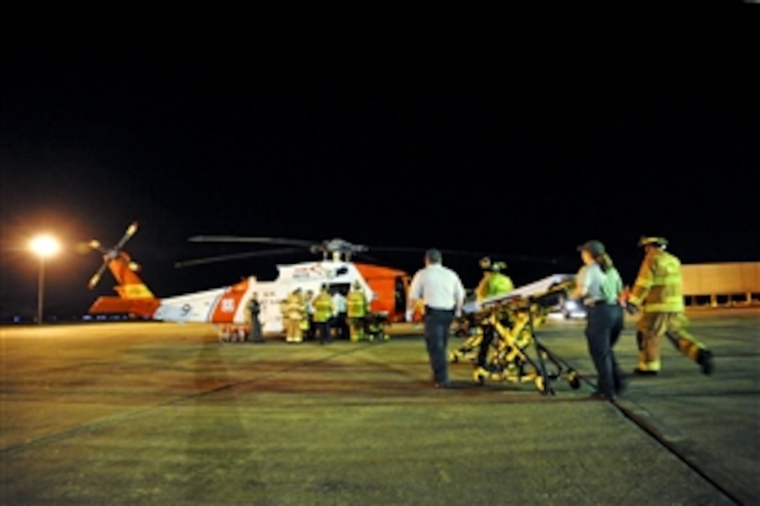 Emergency medical technicians rush a gurney to a waiting HH-60 rescue helicopter and crew from Coast Guard Aviation Training Center Mobile, Ala., on Coast Guard Air Station New Orleans, April 21, 2010. The helicopter crew medevaced multiple survivors from the mobile offshore drilling unit Deepwater Horizon after an explosion and fire caused the crew of the vessel to evacuate. 
