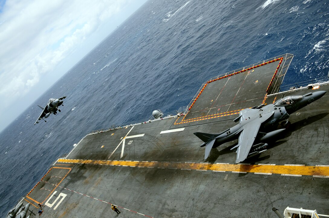 Capt. Scott Farrar, Marine Attack Squadron 311 pilot, lands as British Royal Air Force Flight Lt. Dougie McKay, an exchange pilot with VMA-311, taxis on the deck of the USS Peleliu after landing April 21, 2010, during the squadron’s final predeployment exercise off the coast of California. Six AV-8B Harriers and approximately 80 squadron Marines left Yuma April 15 to participate in their third and final predeployment training evolution. The exercise, which began April 16 and is scheduled to end April 27, included the entire 15th Marine Expeditionary Unit. The squadron is slated to deploy to the Pacific and Indian Oceans with the 15th MEU in May. The main body of the squadron deployed to Japan aboard the USS Essex with the 31st MEU in January. The last time the squadron deployed with the 15th MEU was in 2008.