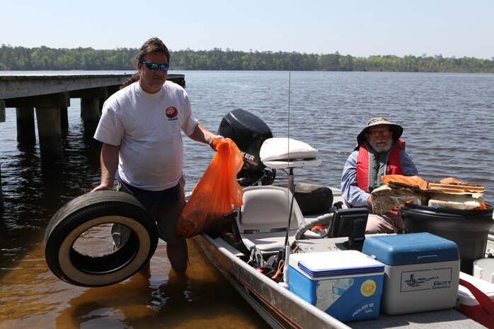 Leo Schmidt (left), a new steward and friend of Elmer Eddy (right), founder of Waterway Stewards, disposes of a tire and a bag of trash found along the shoreline of New River near Marine Corps Base Camp Lejuene, April 22.  These volunteers and service members picked up trash, tires and old toys in celebration of Earth Day.