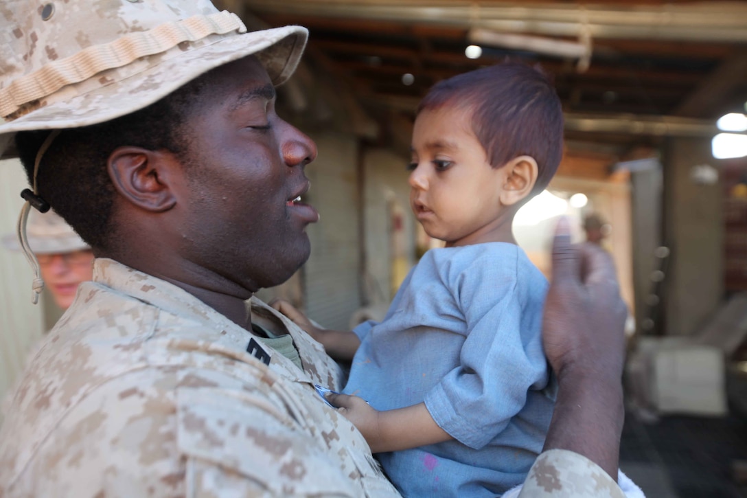 U.S. Navy Corpsman Seaman Valentine Nwosu with 1st Battalion 2nd Marine Regiment (1/2) helps care for a local baby in Musa Qal'eh District Center, Afghanistan, April 22, 2010. Marines and Sailors with 1/2 are participating in combat operations as a part of Operation Enduring Freedom. (U.S. Marine Corps photo by Lance Cpl. Carl Payne)
