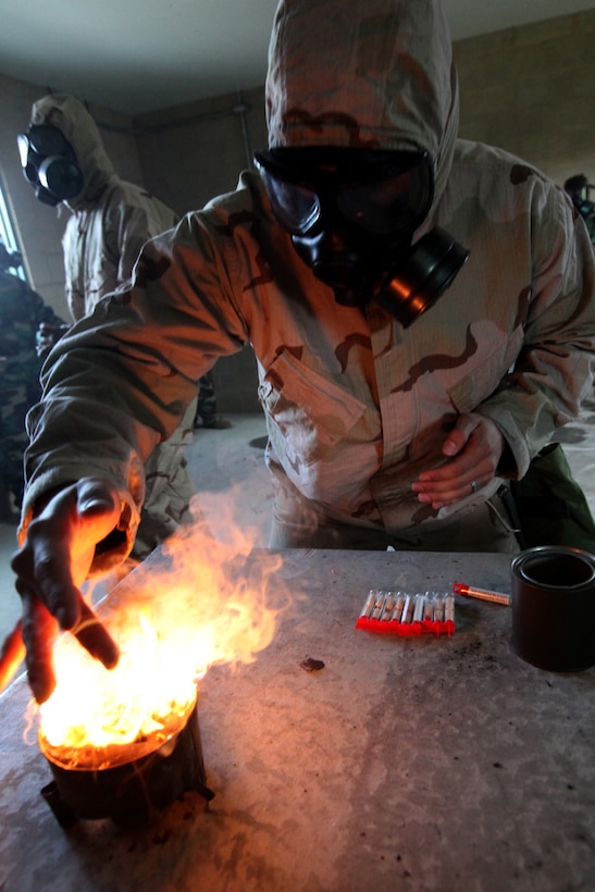 Cpl. Erik Westman, 21, a chemical, biological, radiological and nuclear (CBRN) defense specialist from Charleston, S.C., creates CS gas by burning tablets of CS powder at the 33 area gas chamber. Marines from 9th Communication Battalion, 1st Intelligence Battalion and 1st Radio Battalion took part in an annual confidence mask training exercise to learn how to use their gas mask properly and what to do when faced with a chemical attack. (U.S. Marine Corps photo by Lance Cpl. John M. McCall)