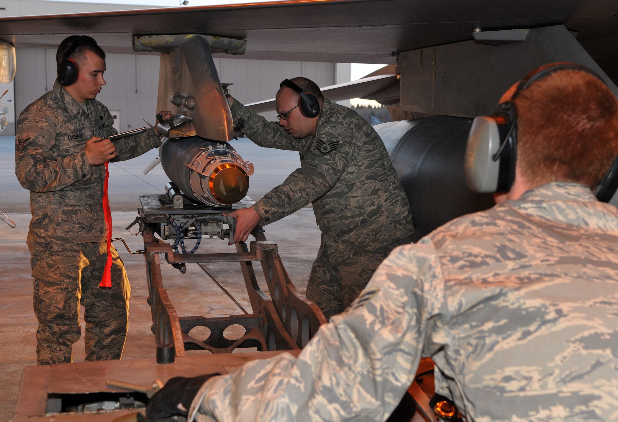 Airman Jon Casebolt, weapons load crewmember, and Staff Sgt. Adam Hatch, weapons load crewchief, work with Senior Airman Troy Bledsoe, weapons load crewmember and jammer operator, to secure an inert Joint Direct Attack Munition GBU-38 onto an F-16 Fighting Falcon during Red Flag-Alaska April 19 at Eielson Air Force Base, Alaska. All of the Airmen are deployed from the 8th Fighter Wing, Kunsan Air Base, Republic of Korea, and assigned to the 8th Aircraft Maintenance Squadron's 80th Aircraft Maintenance Unit Juvats. Red Flag-Alaska is a Pacific Air Forces-directed field training exercise for U.S. and coalition forces under simulated combat conditions. (U.S. Air Force photo/Capt. Shannon Collins) 