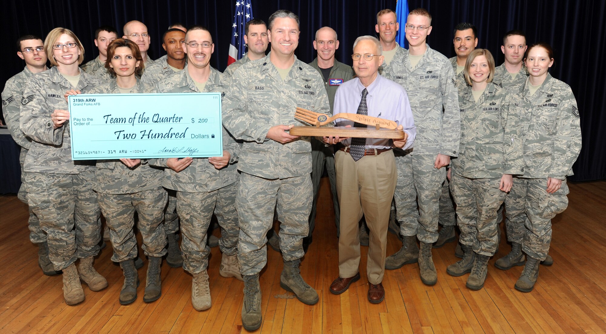 Lt. Col. Samuel Bass, 319th Communications Squadron commander, the CS honorary commander and Airmen from the 319 CS pose for a picture after being named the 319th Air Refueling Wing’s first Quarter Spirit Award winner during the 319 ARW Quarterly Awards at the base theater, April 15. The award recognizes the squadron’s efforts in the total amount of community service hours logged, Airman Against Drunk Driving hours logged, Officer Performance Reports/ Enlisted Performance Reports completed on time and their fit currency (number of current physical health assessments and shot records). (U.S. Air Force photo by Staff Sgt. Suellyn Nuckolls)