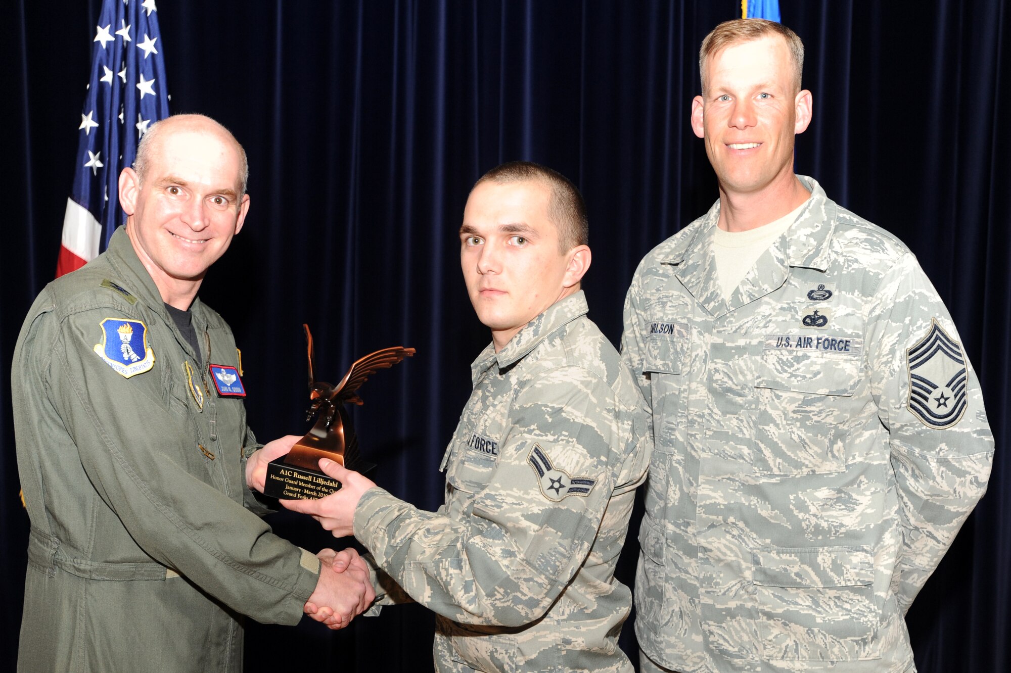 Airman 1st Class Russell Lilljedahl, 319th Logistics Readiness Squadron, receives the Honor Guard Member of the Quarter award from Col. John Quinn, 319th Air Refueling Wing vice-commander and Chief David Carlson, 319th ARW acting command chief during the 319 ARW Quarterly Awards at the base theater, April 15. Military and civilian nominees are selected on the basis of leadership and job performance in primary duties, significant self-improvement, and base and community involvement. (U.S. Air Force photo by Staff Sgt. Suellyn Nuckolls)