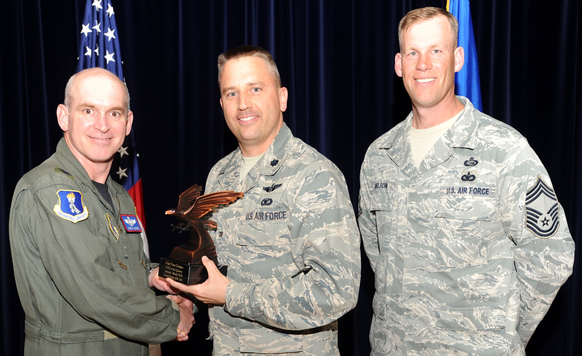 Lt. Col. Darin Driggers, 319th Operations Support Squadron commander accepts the Company Grade Officer of the Quarter award on behalf of Capt. Troy Cooper, 905th Air Refueling Squadron, from Col. John Quinn, 319th Air Refueling Wing vice-commander and Chief David Carlson, 319th ARW acting command chief during the 319 ARW Quarterly Awards at the base theater, April 15. Military and civilian nominees are selected on the basis of leadership and job performance in primary duties, significant self-improvement, and base and community involvement. (U.S. Air Force photo by Staff Sgt. Suellyn Nuckolls)