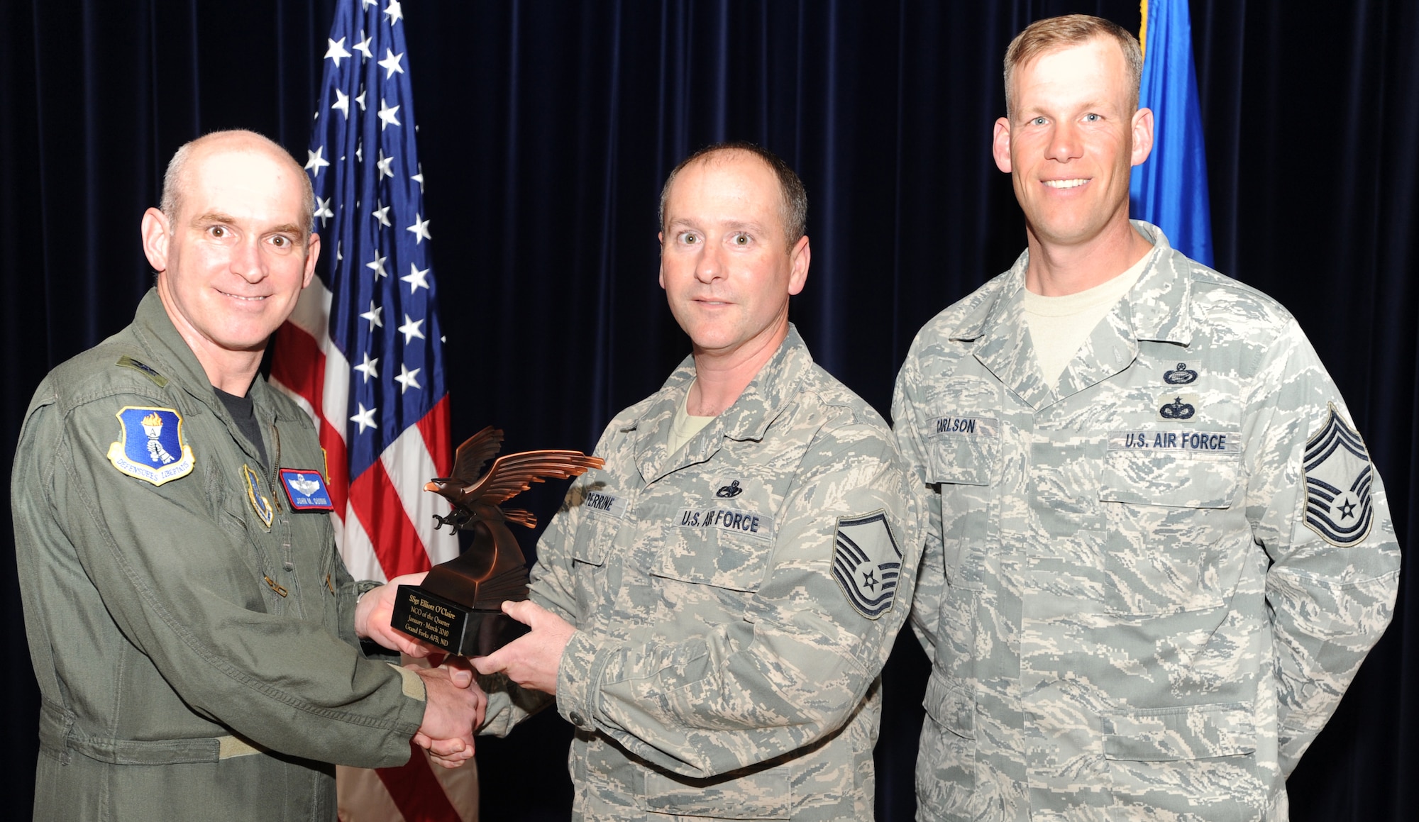 Master Sgt. Thomas Perrine, 319th Maintenance Operations Squadron, accepts the Non-commissioned Officer of the Quarter award on behalf of Staff Sgt. Elliott O’Claire, 319 MOS from Col. John Quinn, 319th Air Refueling Wing vice-commander and Chief David Carlson, 319 ARW acting command chief during the 319 ARW Quarterly Awards at the base theater, April 15. Military and civilian nominees are selected on the basis of leadership and job performance in primary duties, significant self-improvement, and base and community involvement. (U.S. Air Force photo by Staff Sgt. Suellyn Nuckolls))