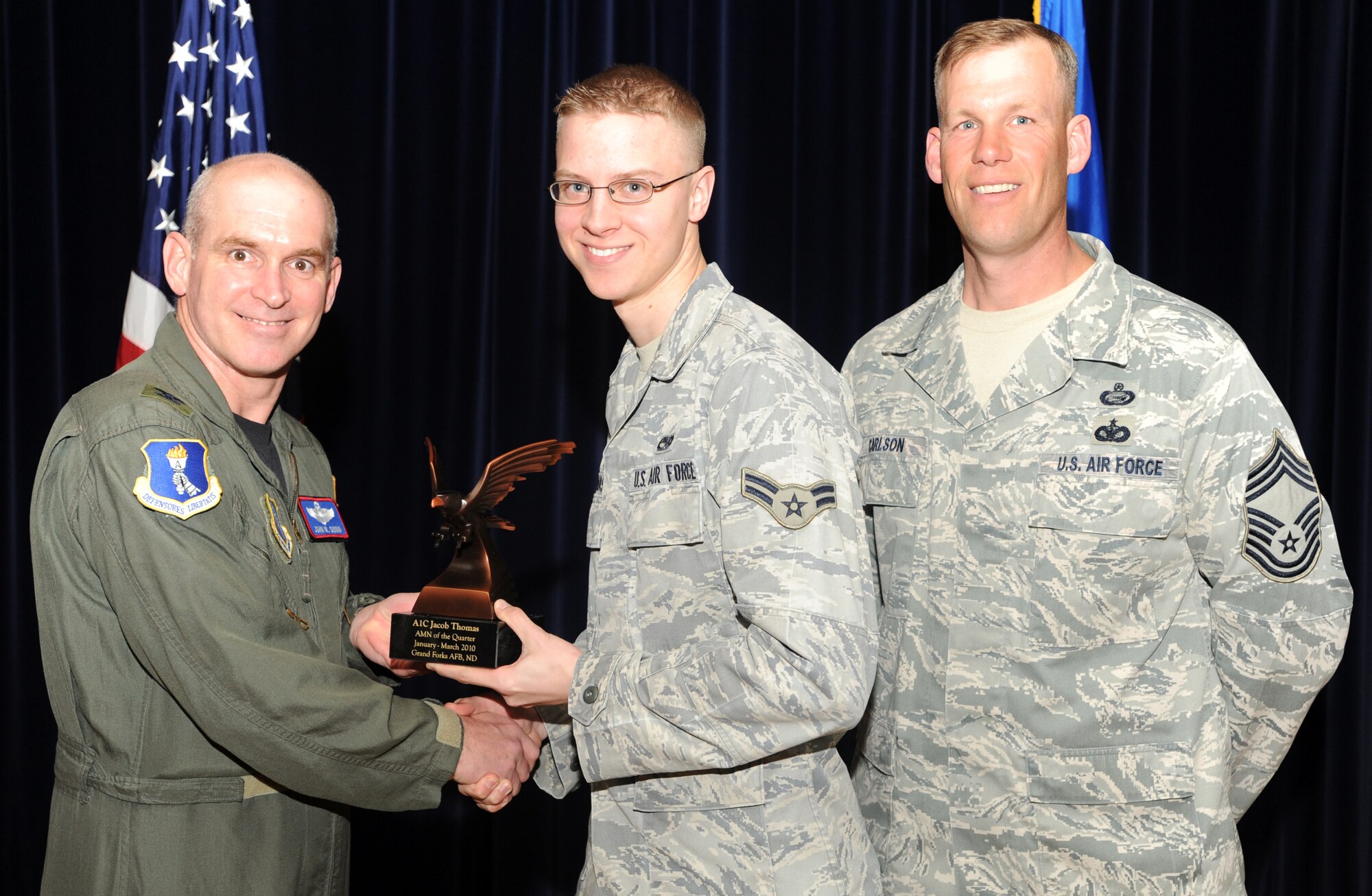 Airman 1st Class Jacob Thomas, 319th Communications Squadron receives the Airman of the Quarter award from Col. John Quinn, 319th Air Refueling Wing vice-commander and Chief David Carlson, 319 ARW acting command chief during the 319 ARW Quarterly Awards at the base theater, April 15. Military and civilian nominees are selected on the basis of leadership and job performance in primary duties, significant self-improvement, and base and community involvement. (U.S. Air Force photo by Staff Sgt. Suellyn Nuckolls)