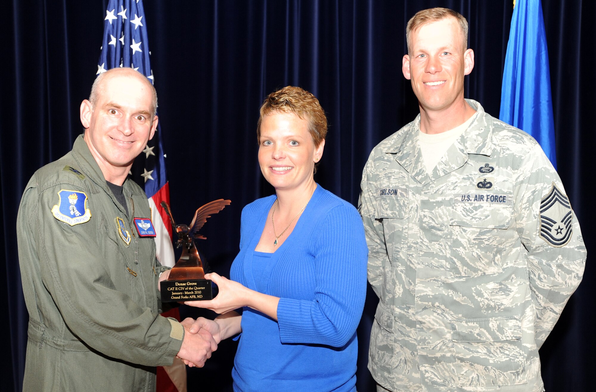 Denae Grove, a civilian with the 319th Medical Operations Squadron, receives the Category Two Civilian award from Col. John Quinn, 319th Air Refueling Wing vice-commander and Chief David Carlson, 319 ARW acting command chief during the 319 ARW Quarterly Awards at the base theater, April 15. Military and civilian nominees are selected on the basis of leadership and job performance in primary duties, significant self-improvement, and base and community involvement. (U.S. Air Force photo by Staff Sgt. Suellyn Nuckolls)
