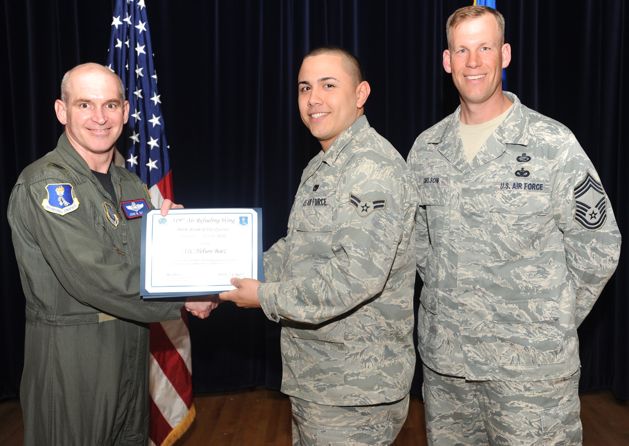 Airman 1st Class Nelson Baez, 319th Logistics Readiness Squadron, receives the Dorm Room of the Quarter award from Col. John Quinn, 319th Air Refueling Wing vice-commander and Chief David Carlson, 319 ARW acting command chief during the 319 ARW Quarterly Awards at the base theater, April 15. Military and civilian nominees are selected on the basis of leadership and job performance in primary duties, significant self-improvement, and base and community involvement. (U.S. Air Force photo by Staff Sgt. Suellyn Nuckolls)