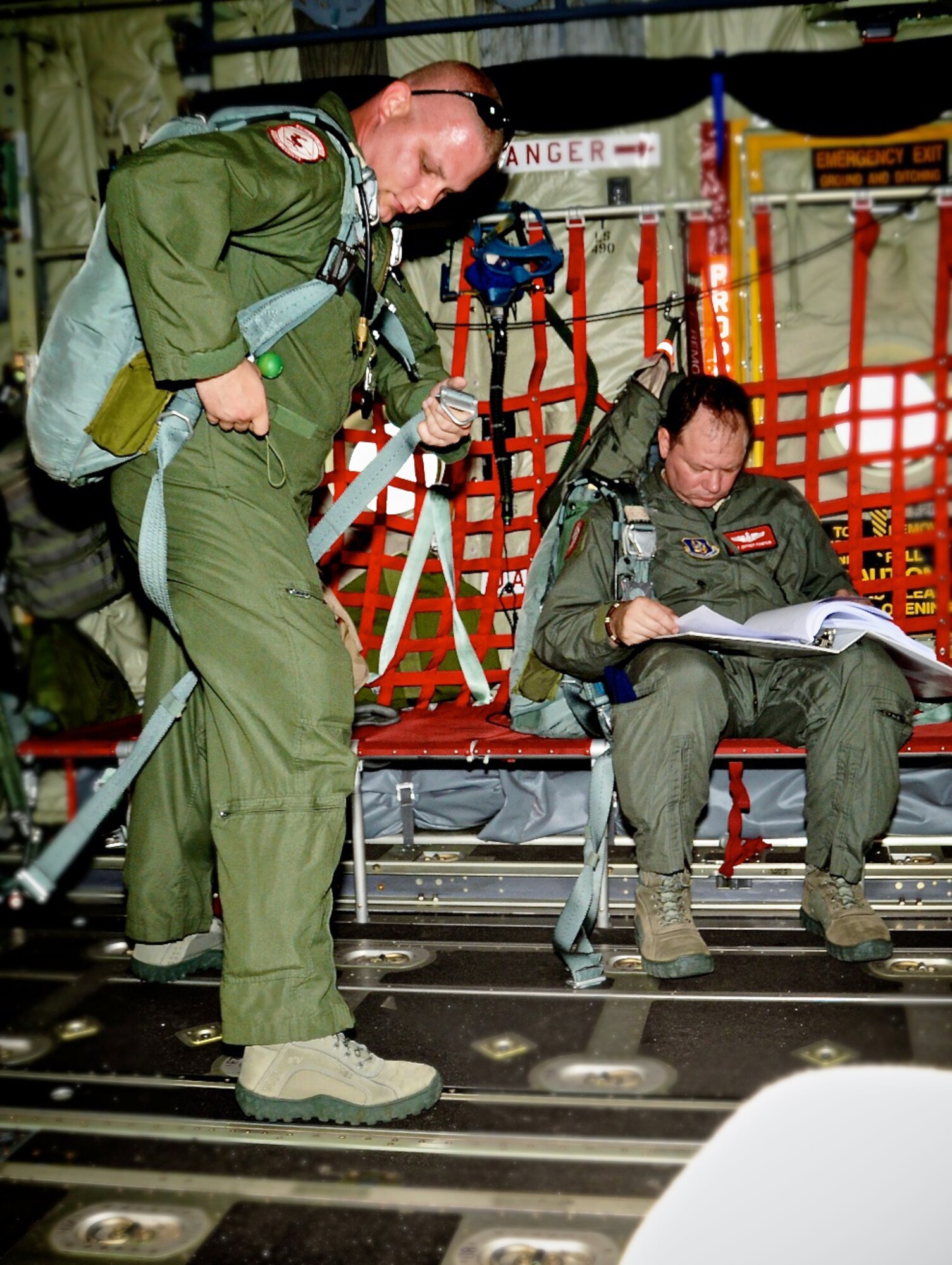 Staff Sgt. Chris Caso adjusts his gear while Staff Sgt. Jeff Fountain reads up on procedures before a training mission April 12, 2010, in Key West, Fla. Sergeants Caso and Fountain are loadmasters assigned to the 815th Airlift Squadron. (U.S. Air Force photo/Tech. Sgt. Tanya King)
