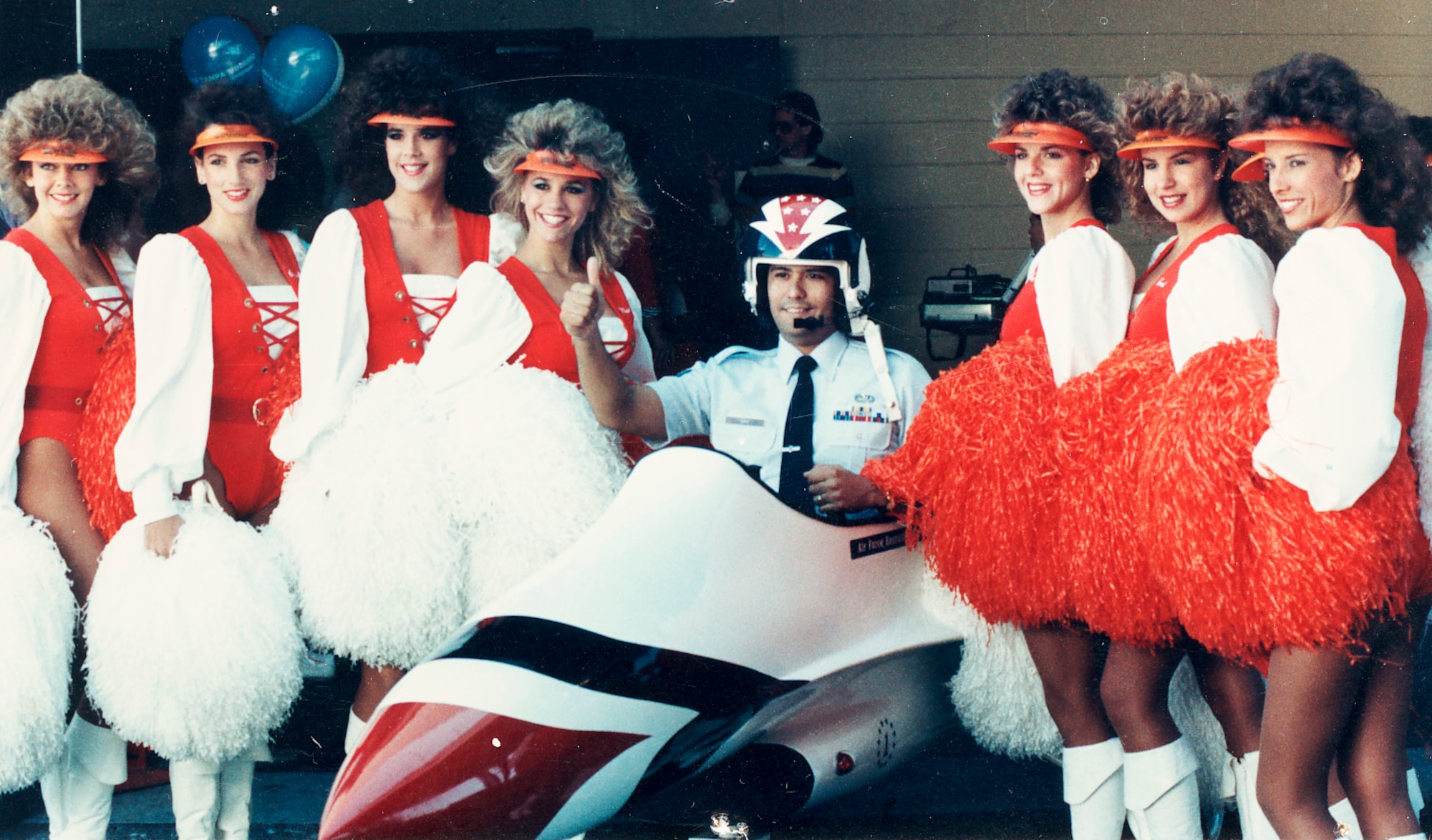 Then Staff Sgt. Douglas Sikat sits in an Air Force mini-jet surrounded by Tampa Bay Buccaneer cheerleaders in the mid-1980s in Tampa, Fla. Now Chief Master Sgt. Sikat will retire from the Air Force April 23 with 30 years of service -- with nearly 26 of those in recruiting. (Courtesy photo)