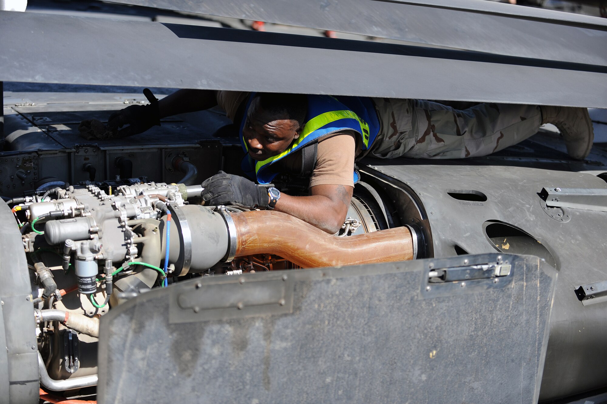 Petty Officer 1st Class Chauvone Taylor, a Navy Customs inspector, checks the inside of an engine compartment for dirt and grease on a UH-60 Black Hawk helicopter, at Joint Base Balad, Iraq, April 15, 2010. Customs personnel inspected 28 helicopters consisting of AH-64 Apaches, CH-47 Chinooks and Black Hawks, to ensure they are clean and contain authorized equipment. The helicopters arrived from forward operating bases throughout Iraq and are being prepared for redeployment back to the United States. (U.S. Air Force photo by Master Sgt. Linda C. Miller/Released)    