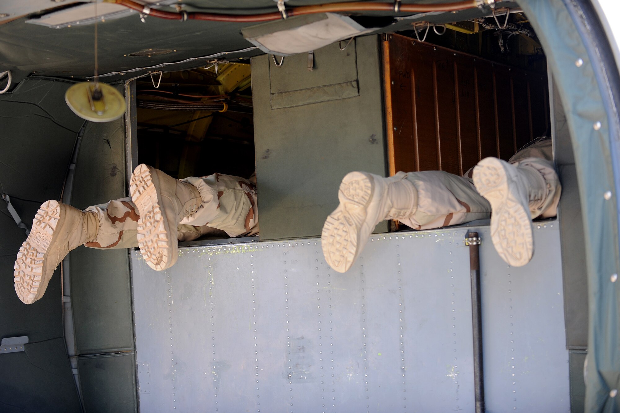 The boots of two Navy Customs members hang out as they inspect the inside compartments of a UH-60 Black Hawk at Joint Base Balad, Iraq, April 15, 2010. Customs personnel inspected 28 helicopters consisting of AH-64 Apaches, CH-47 Chinooks and Black Hawks, to ensure they are clean and contain authorized equipment. The helicopters arrived from forward operating bases throughout Iraq and are being prepared for redeployment back to the United States. (U.S. Air Force photo by Master Sgt. Linda C. Miller/Released)  