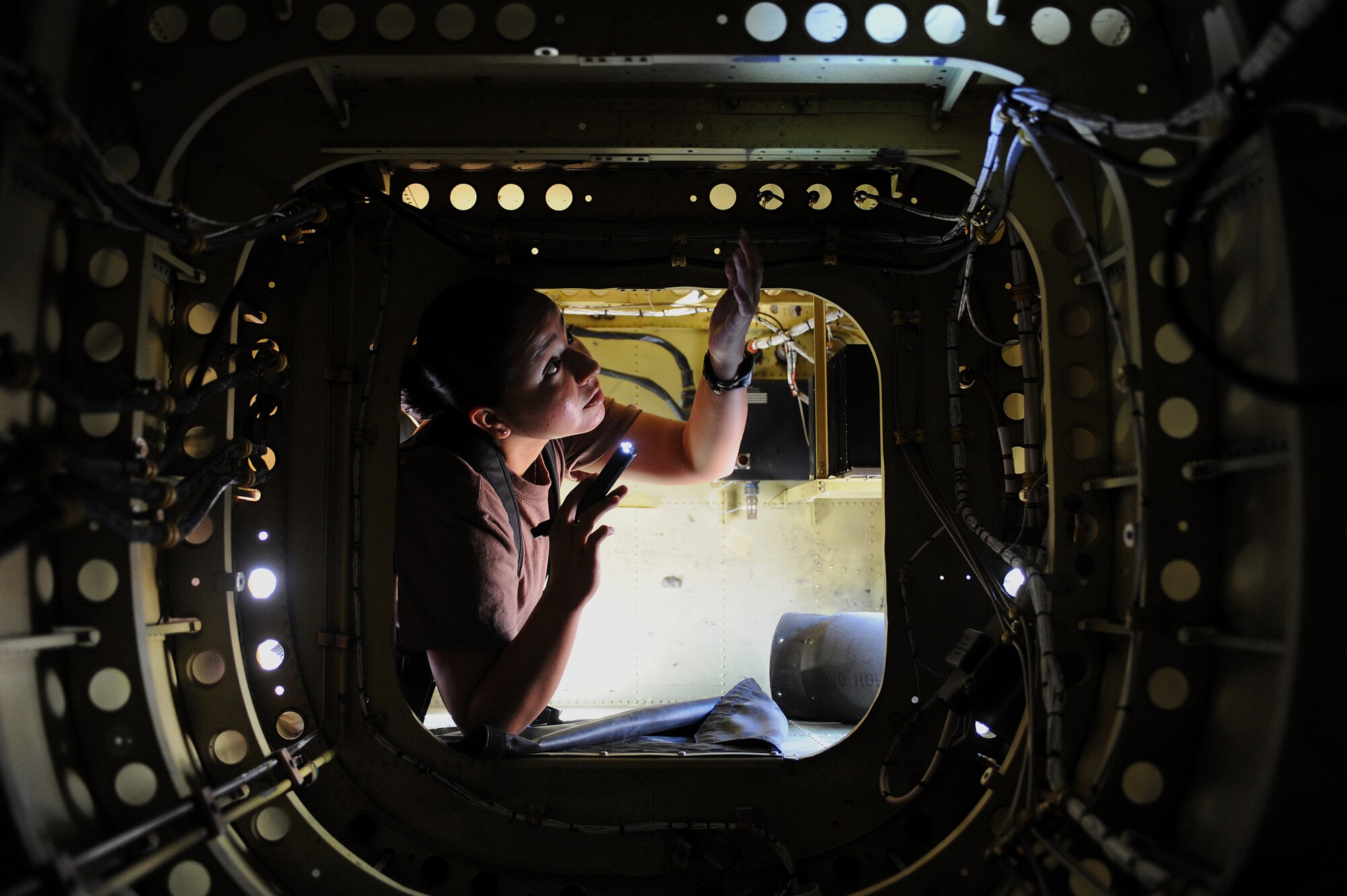 Petty Officer 3rd Class Lluvia Rodriguez, a Navy Customs inspector, checks for dirt and grease inside the tail compartment of an AH-64 Apache helicopter at Joint Base Balad, Iraq, April 15, 2010. Customs personnel inspected 28 helicopters consisting of Apaches, CH-47 Chinooks and UH-60 Black Hawks, to ensure they are clean and contain authorized equipment. The helicopters arrived from forward operating bases throughout Iraq and are being prepared for redeployment back to the United States. (U.S. Air Force photo by Master Sgt. Linda C. Miller/Released)  