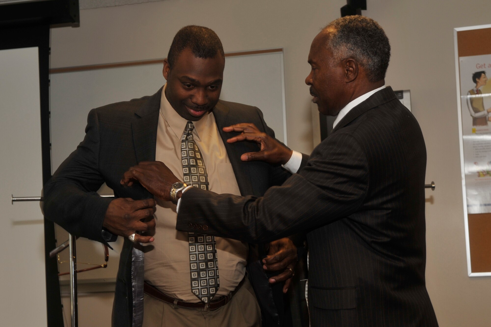 Robert Brisbon (right), image consultant and owner of Brisbon Enterprises in Colorado Springs, helps Master Sgt. Derrick Raynor, North American Aerospace Defense Command /United States Northern Command noncommissioned officer in charge of Reserve component forces, into  a classic American cut suit jacket April 15, during a “Dress for Success” presentation at the Transition Assistance Program five-day workshop. Mr. Brisbon shows military members who are retiring or separating how to choose an interview suit, which is part of TAP’s total program that prepares military members to transition into the civilian workforce. (U.S. Air Force photo/Robb Lingley)