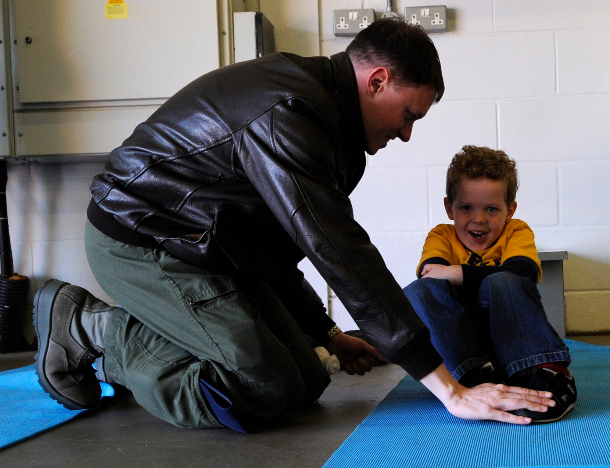 RAF MILDENHALL, England – Capt. Joshua Chambers, 100th Air Refueling Wing, shows his son Hayden how to do crunches during “Bring Your Child to Work Day” April 22.  The event gave children a chance to experience their parent’s job as well as see several displays including the flight simulator.  (U.S. Air Force photo/Staff Sgt. Christopher L. Ingersoll)