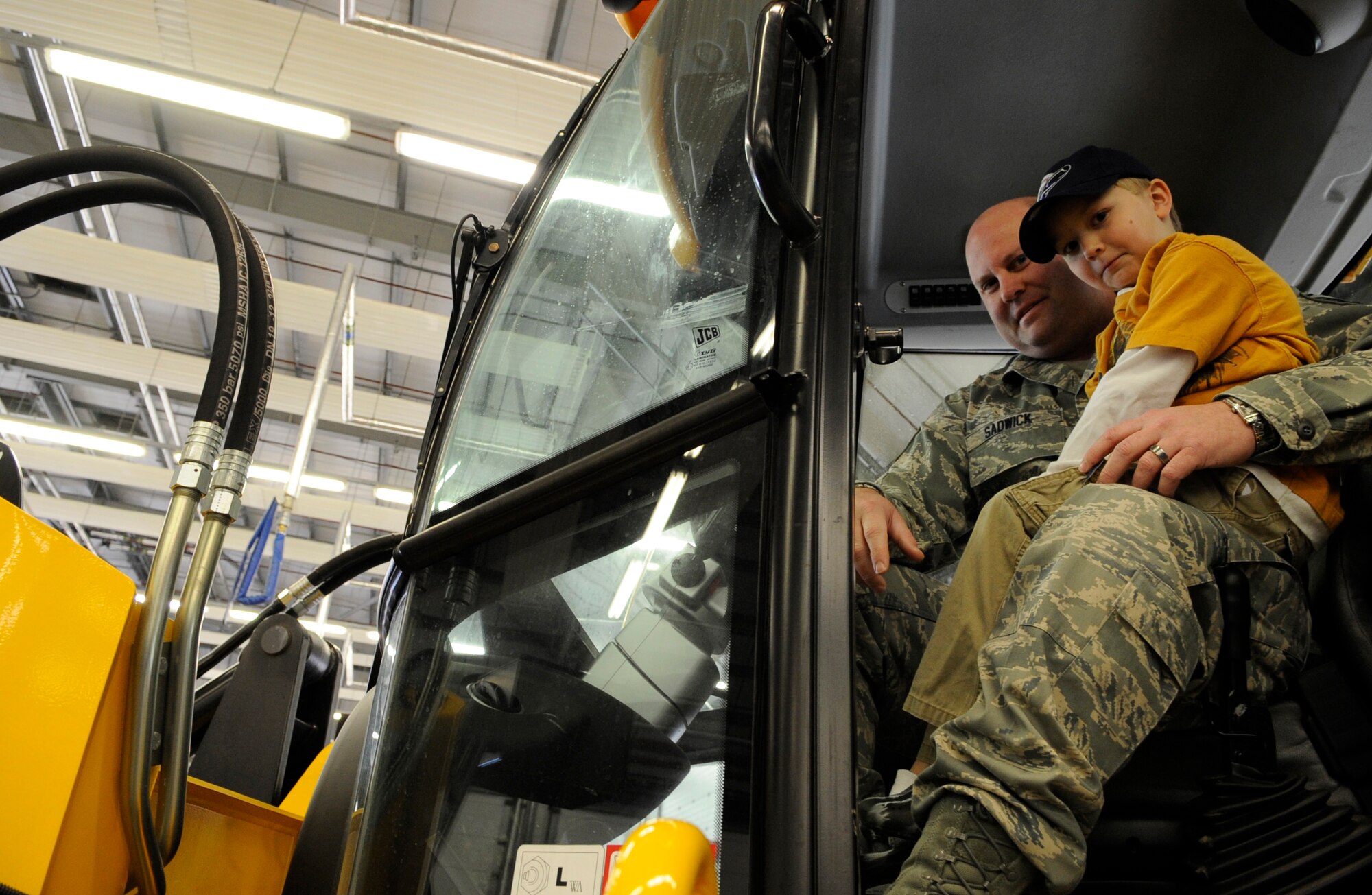 RAF MILDENHALL, England – Master Sgt. Robert Sadwick, 100th Operations Support Squadron, and son his Aidan climb behind the wheel of a bulldozer during “Bring Your Child to Work Day” April 22.  The event gave children a chance to see what their parents do for a living and enjoy some fun displays and activities.  (U.S. Air Force photo/Staff Sgt. Christopher L. Ingersoll)