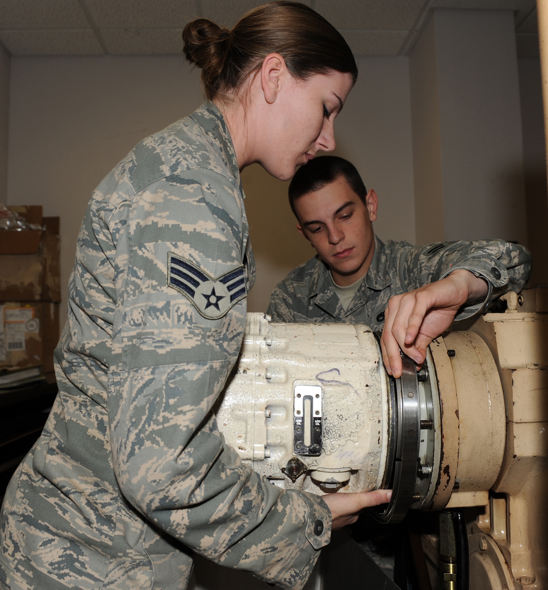 SEYMOUR JOHNSON AIR FORCE BASE, N.C. -- Senior Airman Cathryne Reynolds and Airman 1st Class Tyler McDowell attach a constant speed drive to a K-400 machine here April 20, 2010. The K-400 tests components of non-functioning integrated drive generators to pinpoint the problem on F-15E Strike Eagles. Both Airmen are 4th Component Maintenance Squadron electrical and environmental technicians. Airmen Reynolds is from Perry, Ga. and Airman McDowell is from Augusta, Ga. (U.S. Air Force photo by Airman 1st Class Gino Reyes)