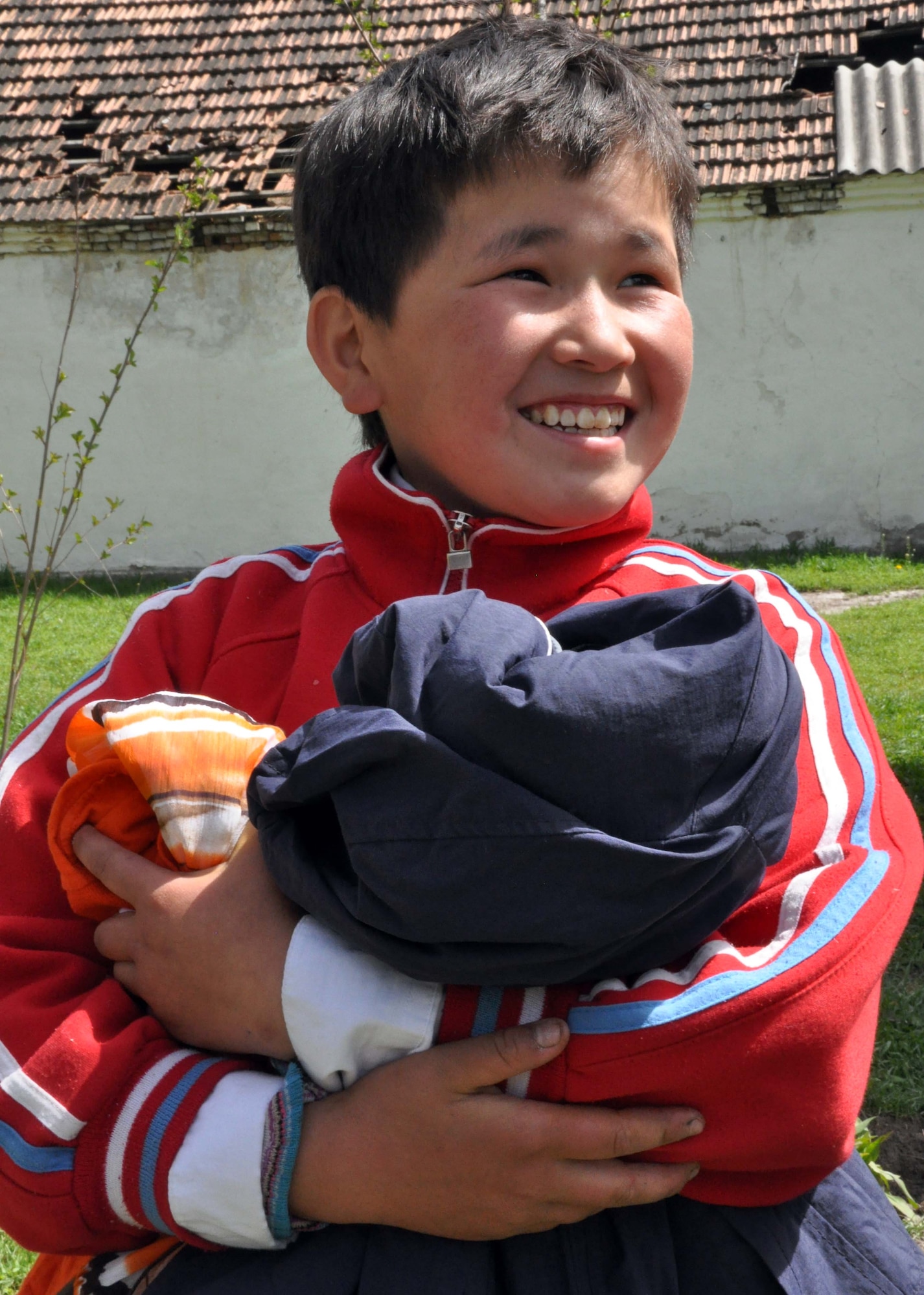 A Kyrgyz boy from the Orto-Suiskaya Boarding School/orphanage for children delights in his new clothing from Airmen at the Transit Center at Manas, Kyrgyzstan, April 22, 2010. Airmen from the Transit Center delivered food and clothing to the residents there as a part of their ongoing humanitarian assistance mission. (U.S. Air Force photo/Staff Sgt. Carolyn Viss)