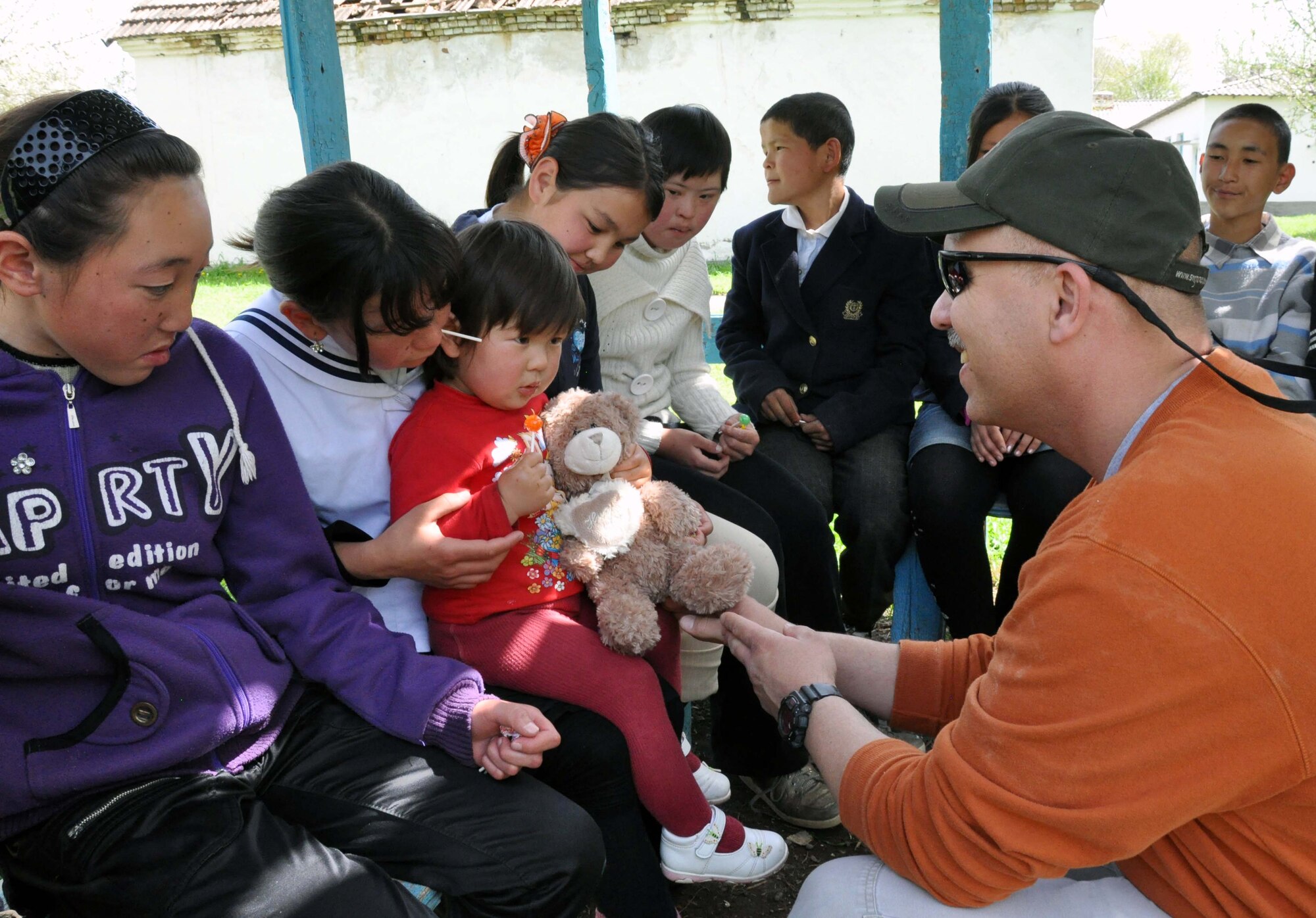 Tech. Sgt. Don Tipton Jr., a chaplain?s assistant from the Transit Center at Manas, Kyrgyzstan, hands a girl from the Orto-Suiskaya Boarding School/orphanage for children a teddy bear during a humanitarian assistance visit April 22, 2010. Airmen from the Transit Center delivered food and clothing to the residents there. (U.S. Air Force photo/Staff Sgt. Carolyn Viss)