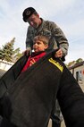 U.S. Air Force Staff Sgt. Cameron Wright, 86th Security Forces Squadron military working dog trainer, helps Ethan Lopez, 5, son of Tech. Sgt. James Lopez, 86th Operations Support Squadron, try on a bite-proof jacket used to train the dogs during Job Shadow Day, Ramstein Air Base, Germany, April 22, 2010. Job Shadow Day in the Kasierslautern Military Community is an annual event in which children have the opportunity to shadow their sponsor or a workplace mentor, completing a half-day on the job in an effort to introduce the young people to the working community through participation. (U.S. Air Force photo by Senior Airman Tony R. Ritter)