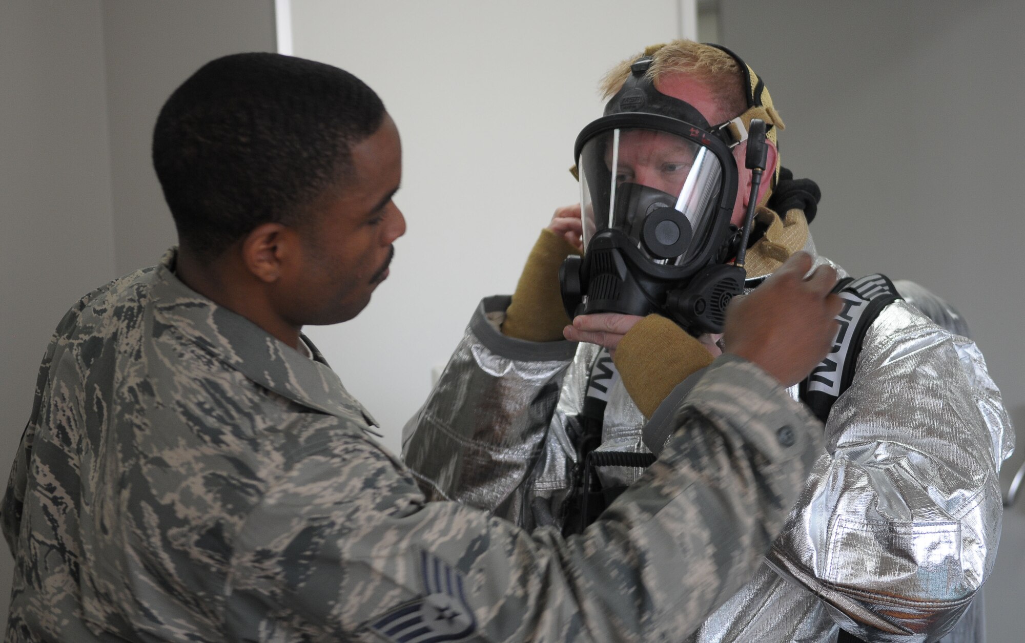 YOKOTA AIR BASE, Japan -- Staff Sgt. Justin Walker, 374th Civil Engineer Squadron crew chief, helps Col. Mark Hicks, 374th Airlift Squadron commander, adjust his mask April 20 during a live fire training exercise. (U.S. Air Force photo/Airman 1st Class Sean Martin)