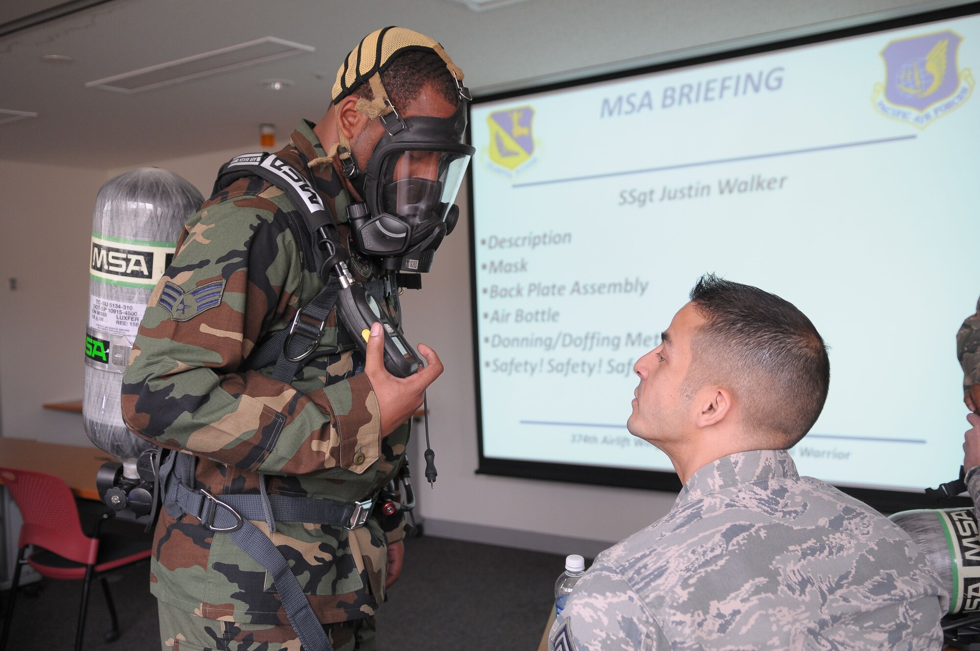 YOKOTA AIR BASE, Japan -- Senior Airman Learone Peagler, 374th Civil Engineer Squadron driver operator, shows Chief Master Sgt. Benjamin Caro, 374th Airlift Wing command chief, how to check the level on his oxygen tank April 20 during a live fire training exercise. (U.S. Air Force photo/Airman 1st Class Sean Martin)