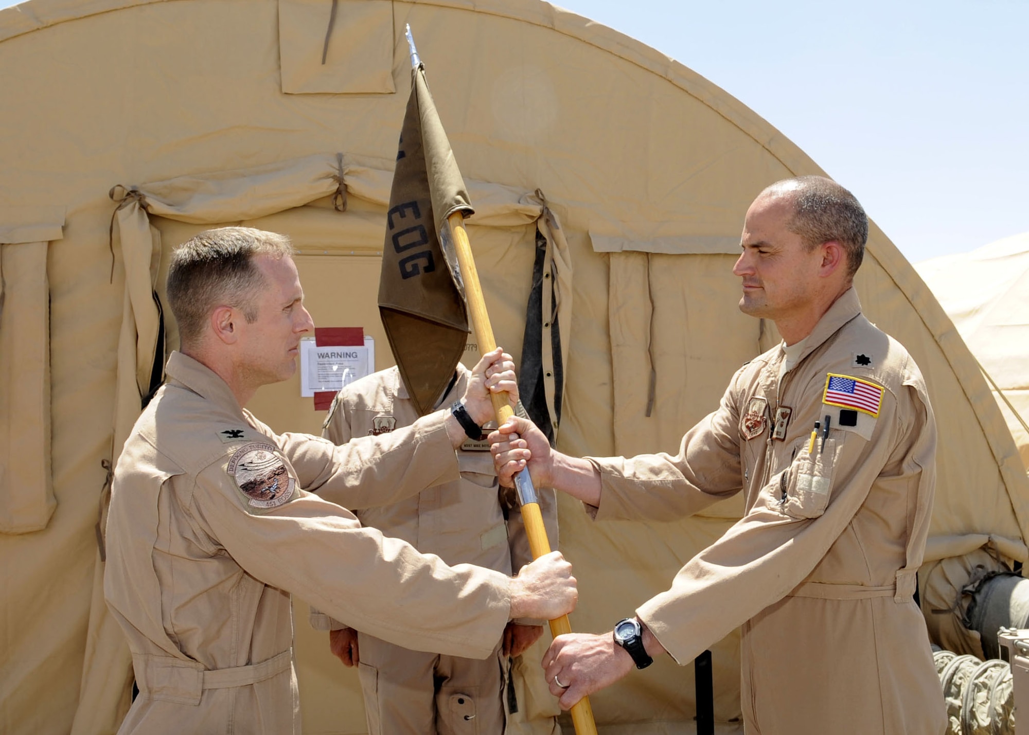 Col. John Cherrey, 451st Expeditionary Operations Group commander, passes the guideon to Lt. Col. Mike Hinsch during the 79th Expeditionary Rescue Squadron activation April 22 at Camp Bastion, Afghanistan.  Colonel Hinsch is deployed to the unit from Davis-Monthan AFB, Ariz.  (U.S. Air Force photo by Senior Airman Nancy Hooks/Released)
