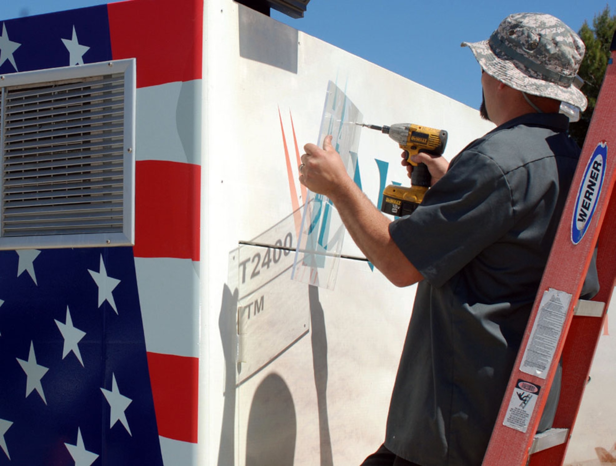 Rich Swatman of Tech Trend Security puts the finishing touches on the new Visterra ATM kiosk on Graeber Street. Tanya Price, Assistant Manager of the Cactus Boulevard Visterra branch, said the old kiosk was beginning to look worn out and the credit union wanted March to have a new one. Bob Hill, the graphic artist who designed the exterior of the kiosk, uses an image of a C-17 assigned to the 729th Airlift Squadron on the front and the image of historic planes on the back. (U.S. Air Force photo by Megan Just)