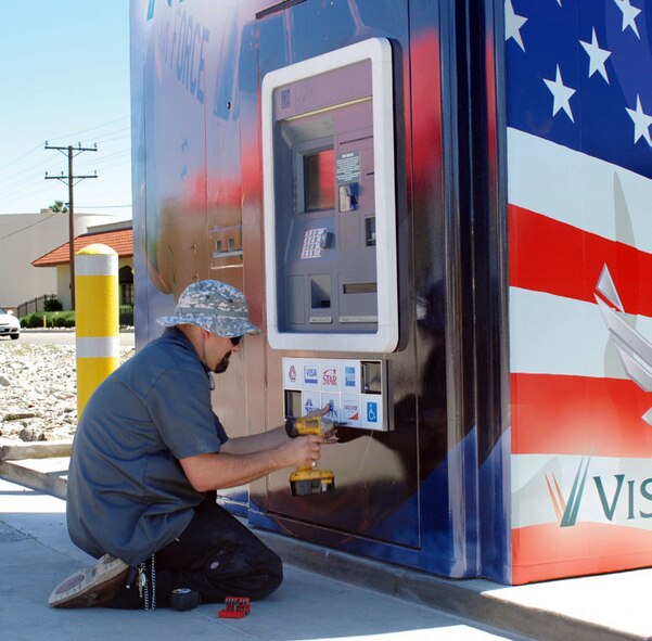 Rich Swatman of Tech Trend Security puts the finishing touches on the new Visterra ATM kiosk on Graeber Street. Tanya Price, Assistant Manager of the Cactus Boulevard Visterra branch, said the old kiosk was beginning to look worn out and the credit union wanted March to have a new one. Bob Hill, the graphic artist who designed the exterior of the kiosk, uses an image of a C-17 assigned to the 729th Airlift Squadron on the front and the image of historic planes on the back. (U.S. Air Force photo by Megan Just)