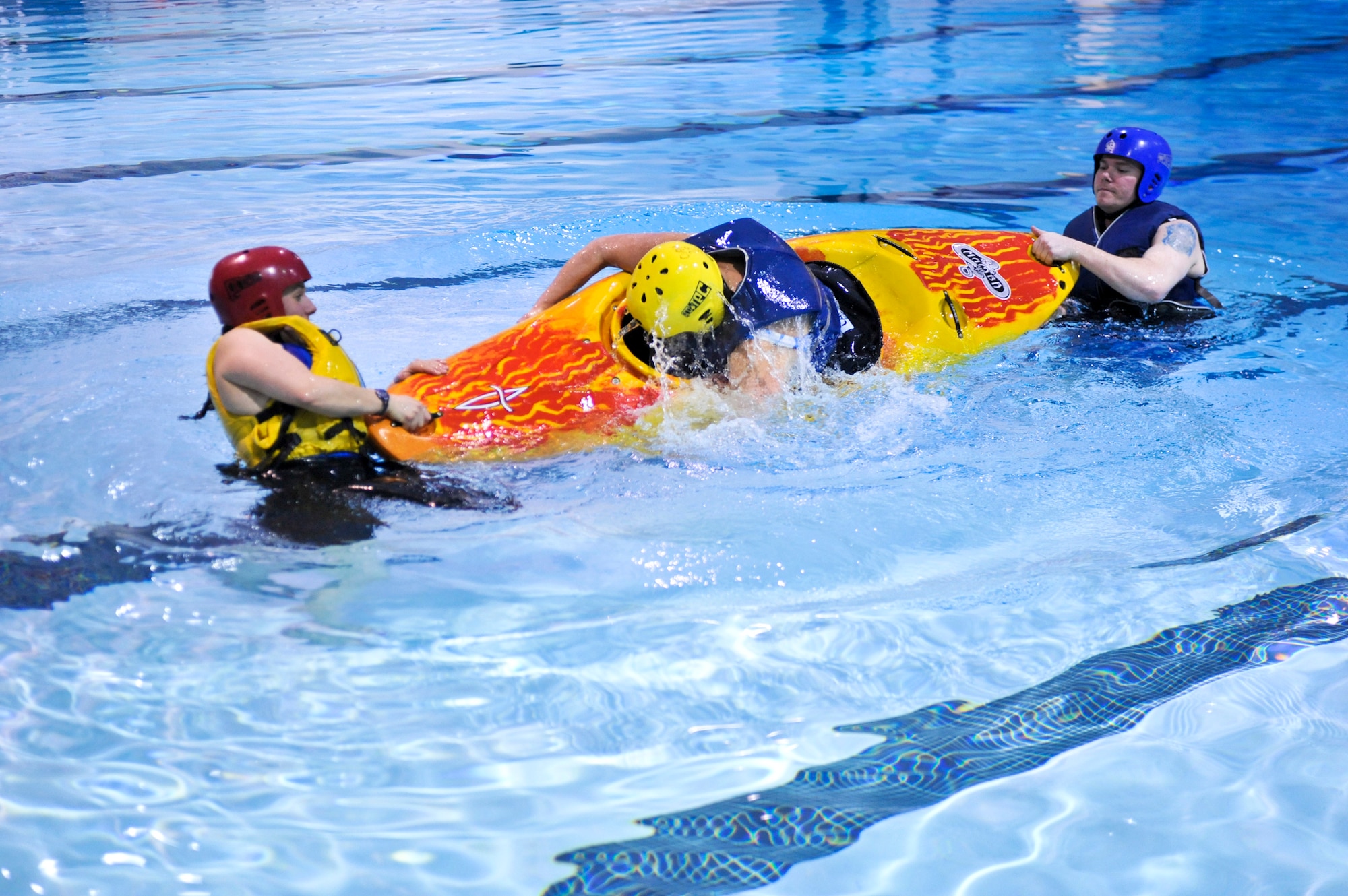 ELMENDORF AIR FORCE BASE, Alaska -- Raina Panarese, left, director of Elmendorf’s Outdoor Adventure Program, and a helper flip a participant during the kayak safety class April 22. Participants were taught to lean forward and grab hold of the kayak in order to achieve a fast and safe exit. Kayak safety classes are required for anybody renting kayaks from Elmendorf’s Outdoor Recreation Center, or for anybody attending one of OAR’s kayaking trips. (Air Force photo by Airman 1st Class Christopher Gross)
