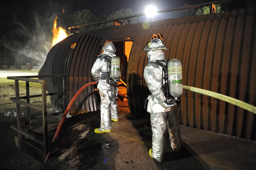 U.S. Air Force and Navy firefighters advance a water hose, also called a handline, into a simulated aircraft to assist interior firefighting crews at Joint Base Charleston, S.C., April 21, 2010. The firefighters awaiting direction outside were part of a Rapid Intervention Team, or RIT. The joint-service fire training was conducted at the crash-fire rescue training facility as part of a 24-hour, live-fire training session each base firefighter is required to complete annually. (U.S. Air Force photo/James M. Bowman/released)
