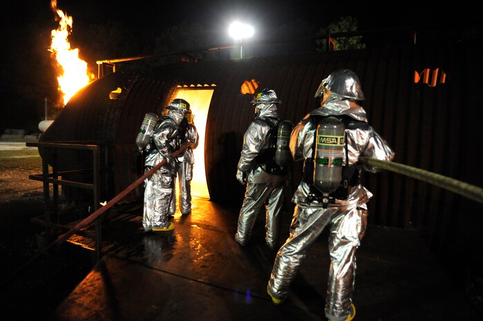 U.S. Air Force and Navy firefighters crews make their initial entry into a live fire during a training session at the crash-fire rescue training facility at Joint Base Charleston, S.C., April 21, 2010. The firefighters awaiting direction outside were part of a Rapid Intervention Team, or RIT. The joint fire training was conducted with Air Force and Navy firefighters from Joint Base Charleston at the crash-fire rescue training facility as part of a 24-hour, live-fire training session each base firefighter is required to complete annually. (U.S. Air Force photo/James M. Bowman/released)