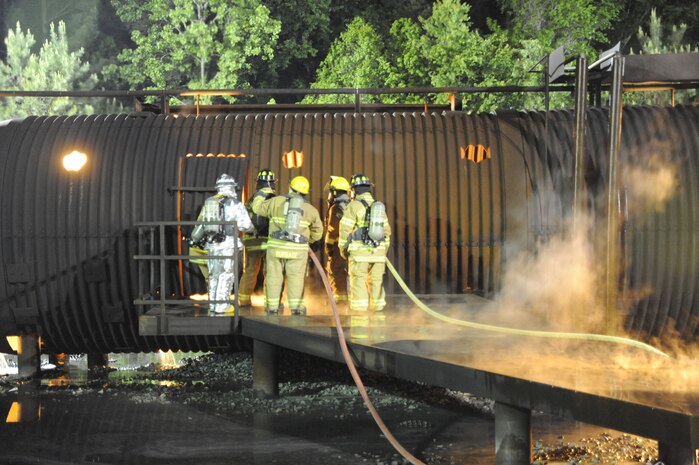 Air Force and Navy firefighters conduct safety checks prior to making initial entry into a simulated aircraft at Joint Base Charleston, S.C., April 21, 2010. The joint-service fire training was conducted at the crash-fire rescue training facility as part of a 24-hour, live-fire training session each base firefighter is required to complete annually. (U.S. Air Force photo/James M. Bowman/released)