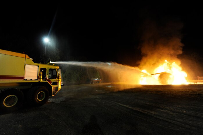 U.S. Air Force and Navy firefighters use a P-23 fire truck to perform a fire suppression oscillation operation on a simulated aircraft at Joint Base Charleston, S.C., April 21, 2010. The simulation was part of a 24-hour, live-fire training session each base firefighter is required to complete annually. The P-23 has two tanks; one holds 3,300 gallons of water, and the other tank holds 500 gallons of fire-retardant foam. (U.S. Air Force photo/James M. Bowman/released)