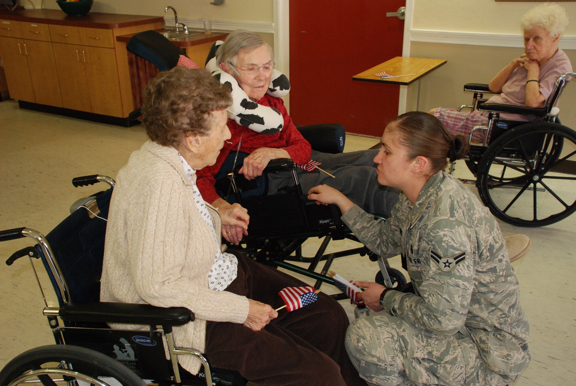 Airman 1st Class Jennifer Dowling, 90th Civil Engineer Squadron, chats with residents Alice and Pauline in the Cheyenne Life Care Center on April 7.