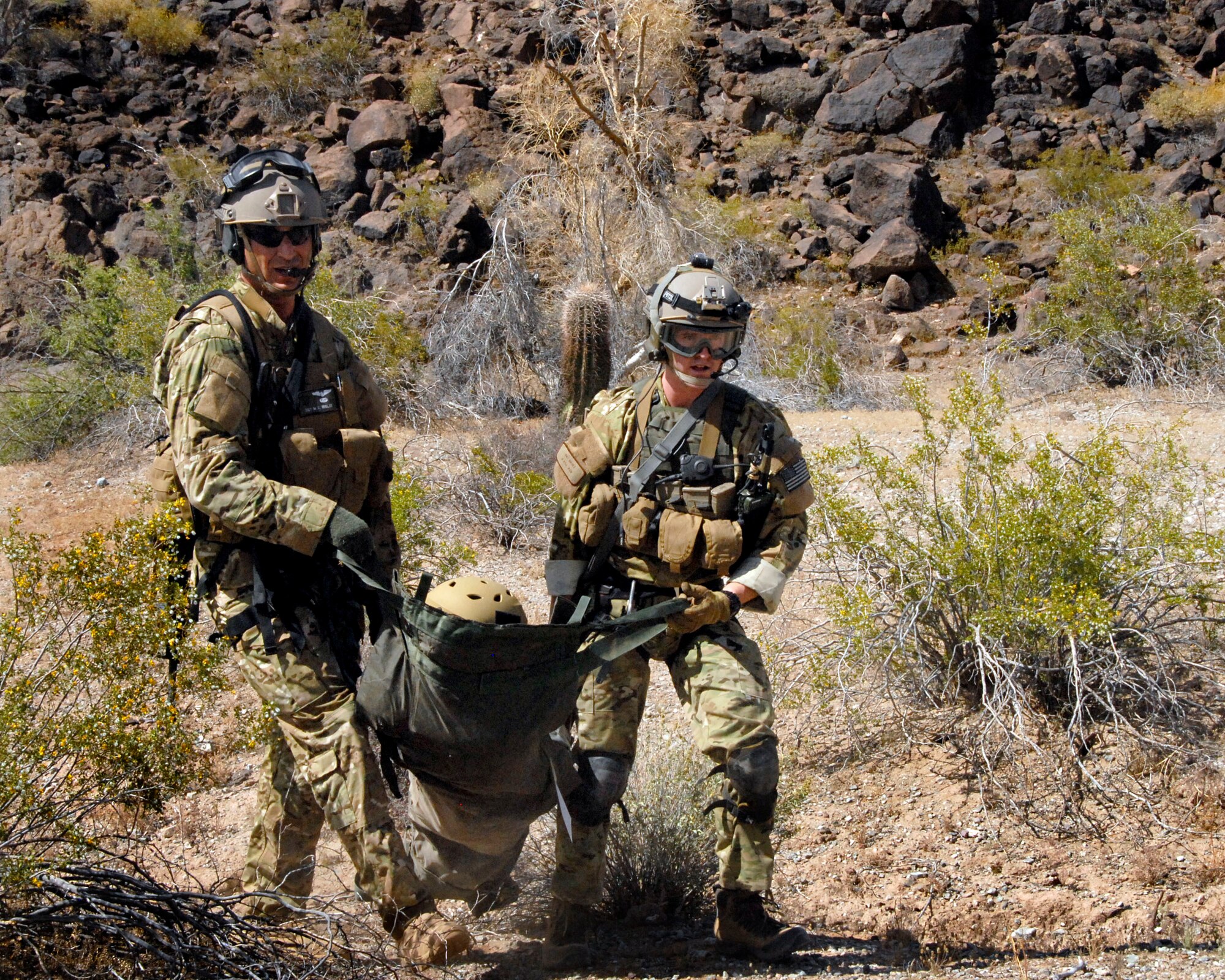 Pararescuemen participating in an Angel Thunder combat search and rescue mission at the Barry M. Goldwater range in the Sonoran Desert outside Davis-Monthan Air Force Base carry the volunteer survivor to the HH-60G Pave Hawk rescue helicopter. (U.S. Air National Guard photo/Airman 1st Class Jessica Green)