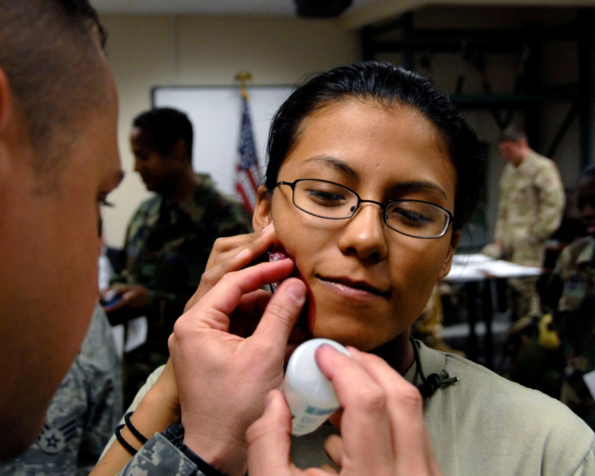 Tech Sgt. Wayne Johnson, with the 336th Training Group based out of Fairchild Air Force Base, Wash., applies simulated injury makeup to Airman 1st Class Britney Garcia, with the 355th Logistics Readiness Squadron at Davis-Monthan AFB, Tucson, Ariz. before heading out to participate in an Angel Thunder combat search and rescue exercise scenario April 19, 2010. (U.S. Air National Guard photo/Airman 1st Class Jessica Green)