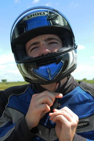 Senior Airman Jeremy Jones, 9th Intelligence Squadron imagery systems maintenance journeyman, straps on his motorcycle helmet before he leaves work to ride home April 22, outside the 9IS. A safety helmet is required in order to operate a motorcycle on military installations. (Air Force photo by Airman 1st Class Sandra Healy)