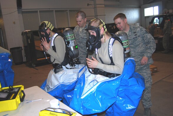 Senior Airman Rebecca Chase, and Airman 1st Class Brittany Musha, 341st Civil Engineer Squadron emergency management technicians, remove their Level A suits and their self contained breathing apparatus after simulating entry and detection hazardous materials. (U.S. Air Force photo/Airman 1st Class Kristina Overton)
