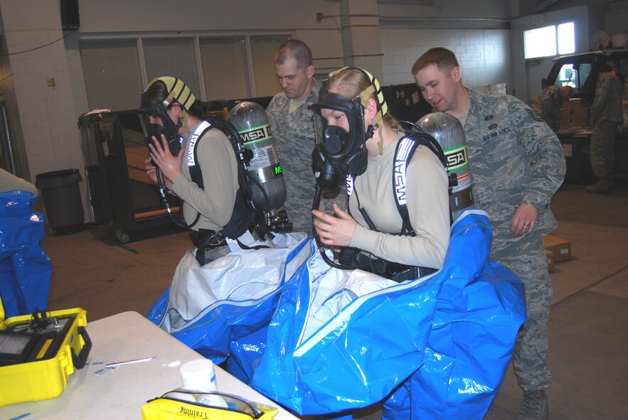 Senior Airman Rebecca Chase, and Airman 1st Class Brittany Musha, 341st Civil Engineer Squadron emergency management technicians, remove their Level A suits and their self contained breathing apparatus after simulating entry and detection hazardous materials. (U.S. Air Force photo/Airman 1st Class Kristina Overton)