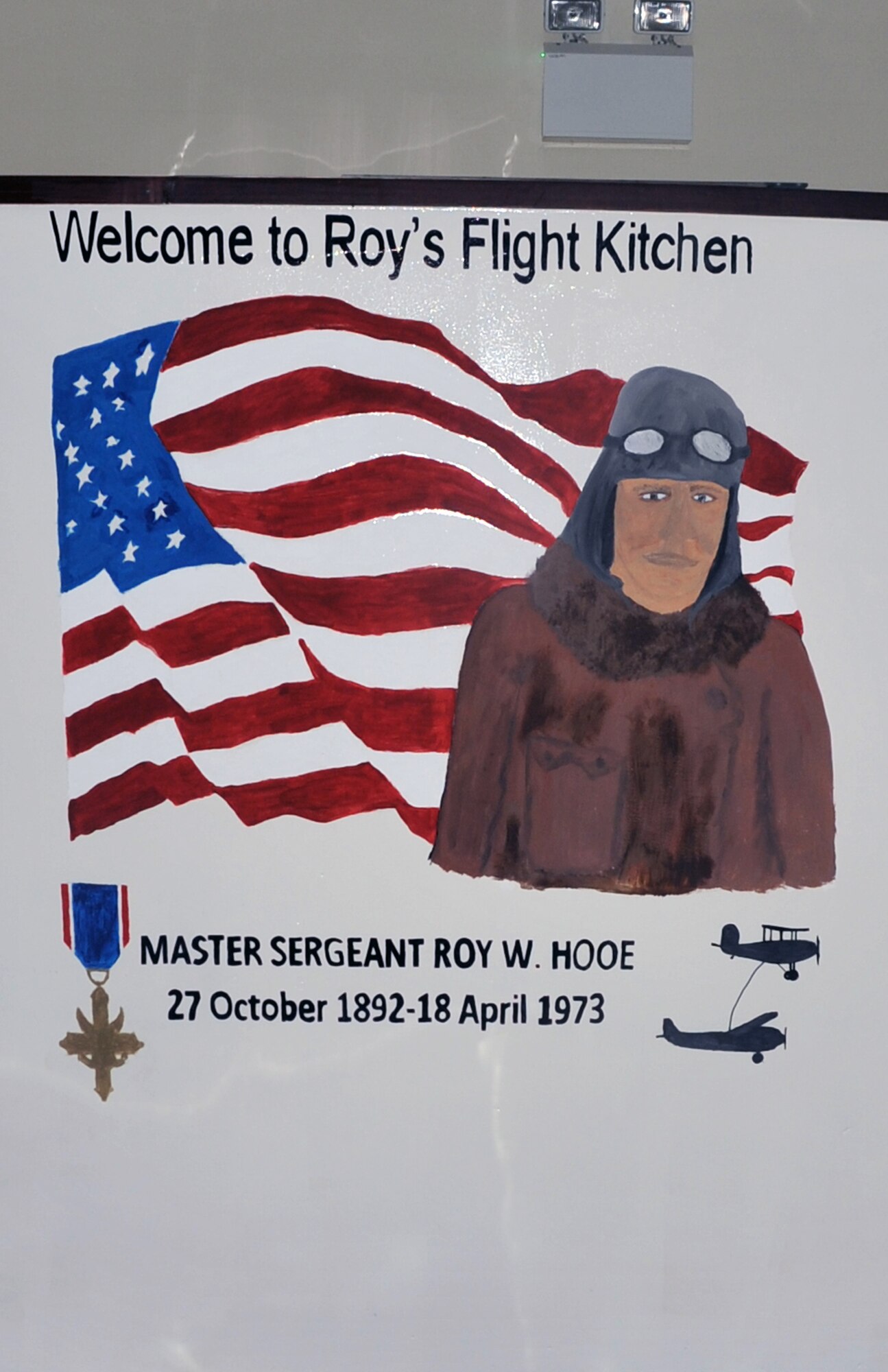 This is a photo of the mural painted in honor of Master Sgt. Roy Hooe at Roy's Flight Kitchen at the operations area of the 380th Air Expeditionary Wing at a non-disclosed base in Southwest Asia.  A 2001 inductee to the Airlift/Tanker Association Hall of Fame, Sergeant Hooe is most widely known for his work as an ?airborne mechanic? on the famed ?Question Mark? flight, according to AMC history. Sergeant?s Hooe?s famed flight was for 151 hours beginning on Jan. 1, 1929. Then Staff Sgt. Hooe was responsible for keeping the ?Question Mark? aloft during a record-setting endurance flight, which at one point required him to go outside the aircraft on a catwalk to make engine repairs. Airmen from the 380th Air Expeditionary Wing who coordinated and completed the mural include Master Scott Sturkol, Tech. Sgts. Johnette Chun and Bobby Ramos, and Senior Airmen Levar Kinard, Abdul Montaser and Priscilla Llanos. (U.S. Air Force Photo/Master Sgt. Scott T. Sturkol/Released)
