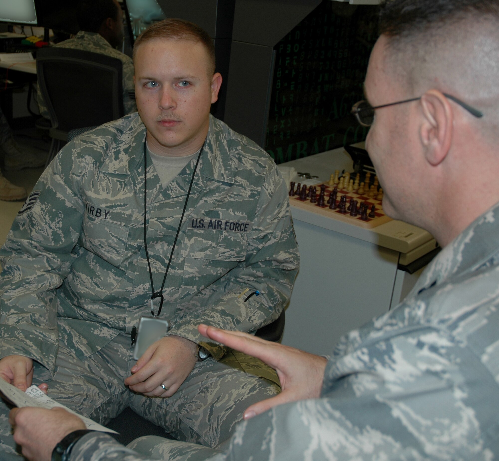 Staff Sgt. Jonathan Kirby, left, NCO in-charge of combat coding, and Capt. Rodney Bagley, Theater Maintenance and Software Development chief, discuss paperwork in the combat-coder office April 16, 2010, in the Combined Air and Space Operations Center. (U.S. Air Force photo illustration/Senior Airman Dillon White/released)