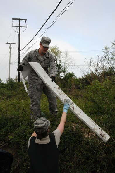 Staff Sgt. Daniel Hansen, 211th Engineering Installation Squadron, electronic technician hands garbage he found along the steam bank of the stream in Area 1 at Fort Indiantown Gap, Annville, Pa., to Master Sgt. Andrea Stine, 211th Engineering Installation Squadron, personnel. These two Airmen were part of a group of nine that volunteered to participate in an Earth Day clean-up, April 22. (U.S. Air Force photo by Airman 1st Class Claire Behney